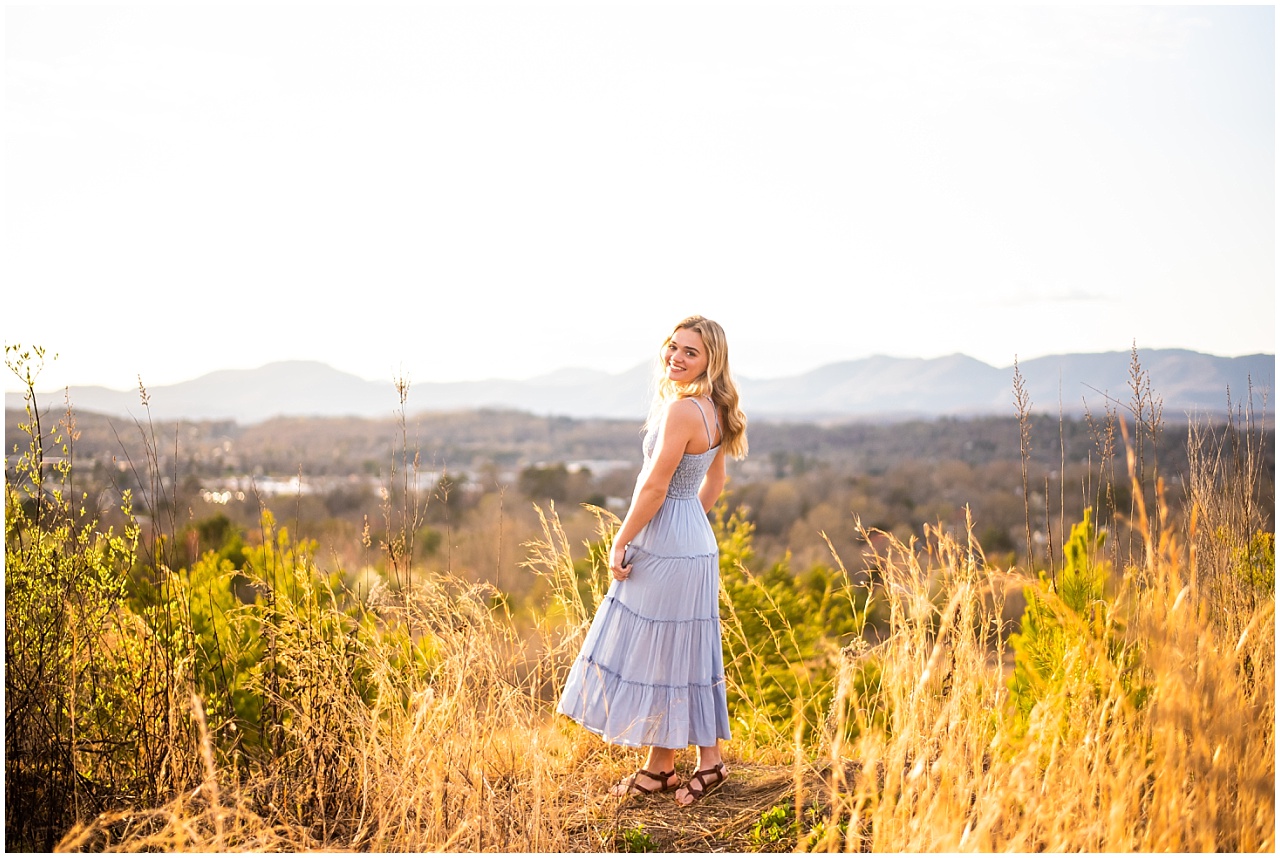 Blonde girl in a field wearing a light blue dress with sandals.
